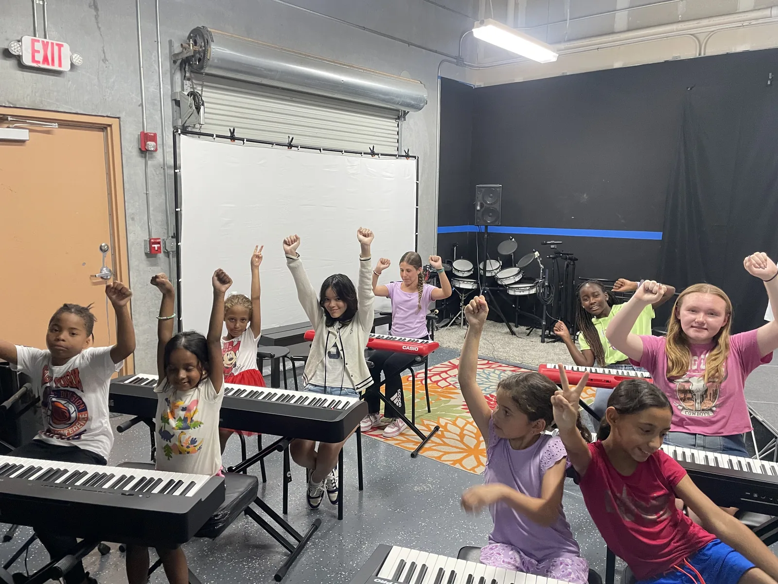 Children cheering at their keyboards during a group piano class