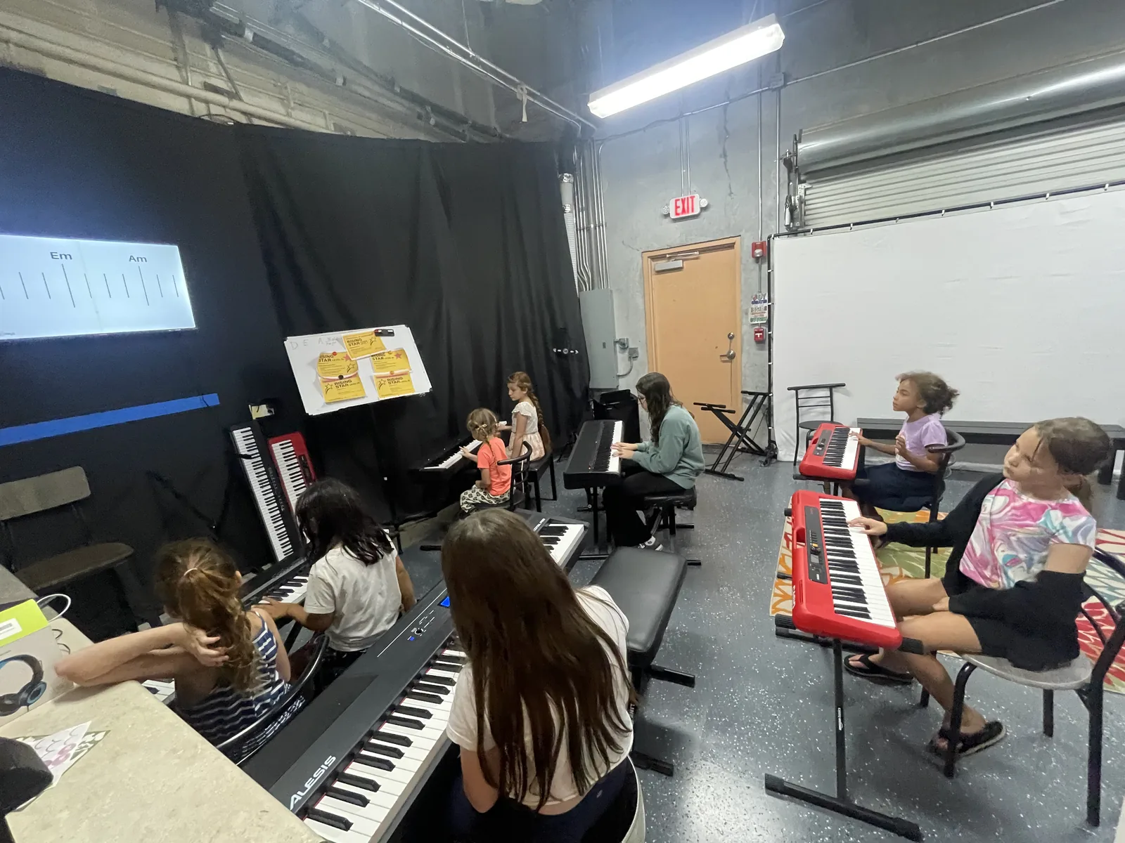 Students practicing at keyboards during a piano lesson in the studio